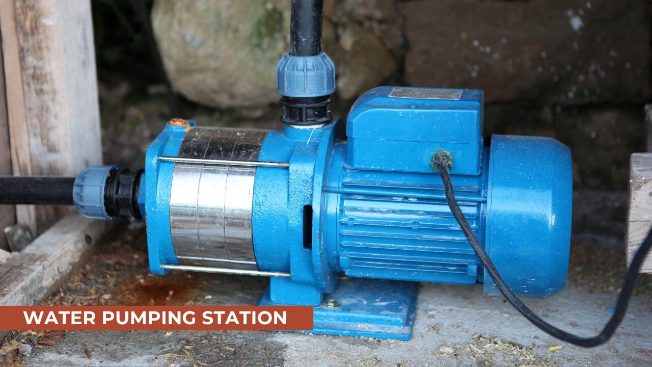 Close-up of a blue water pump station with connected piping, used for irrigation or water management, placed on a wooden surface in a rustic setting