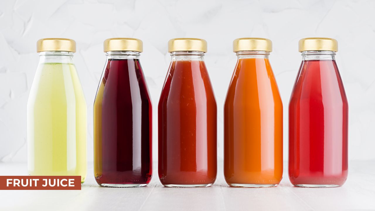 Five glass bottles filled with different colored fruit juices, including yellow, red, and orange juices, each sealed with a golden cap